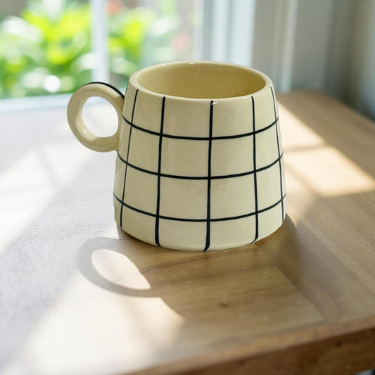 Handcrafted beige ceramic mug with black grid pattern – 300ml modern coffee cup on wooden table by Lupaava