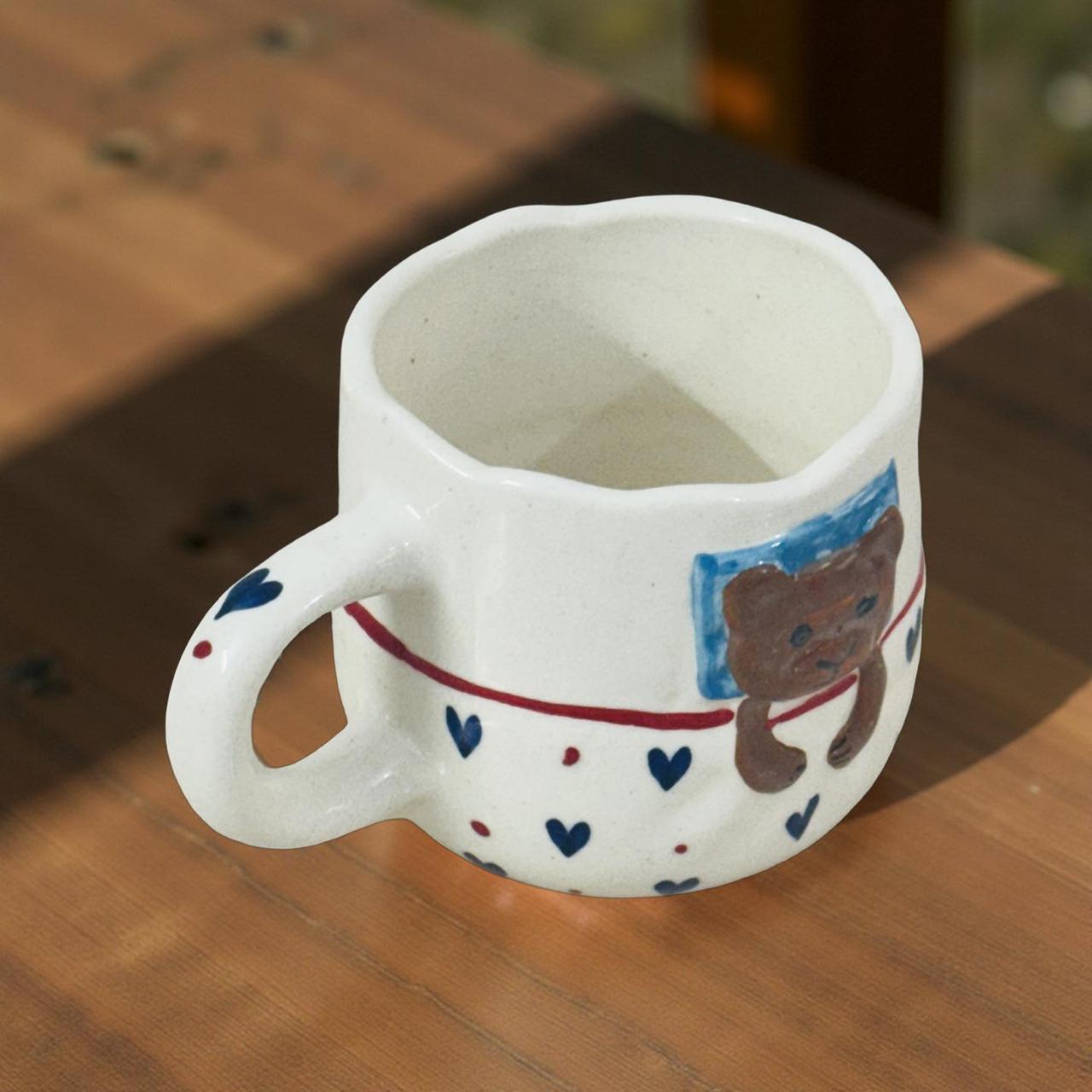 white ceramic coffee mug with bear print kept on a wooden finish table