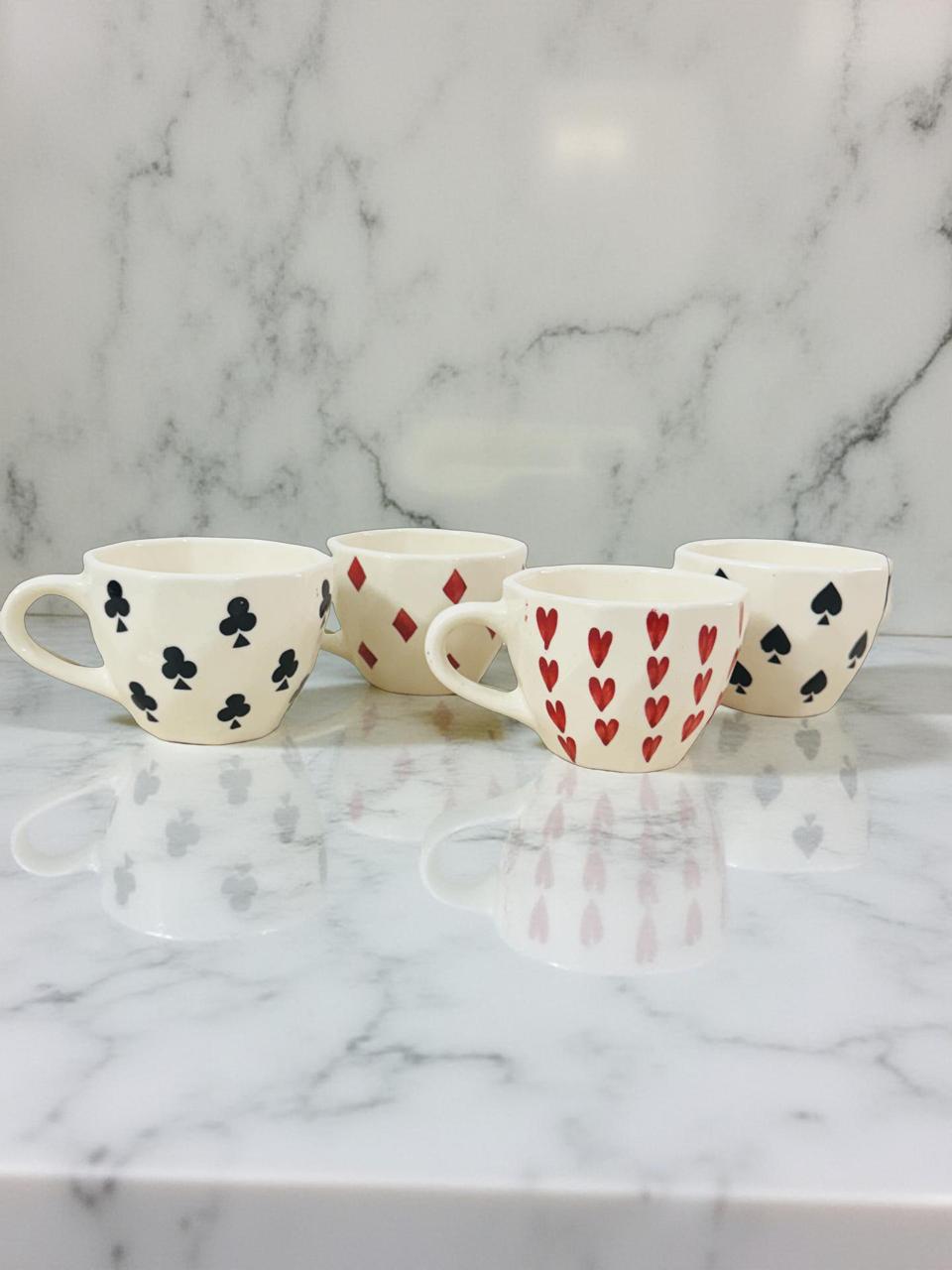 playing card theme ceramic coffee mugs are kept on a white granite surface