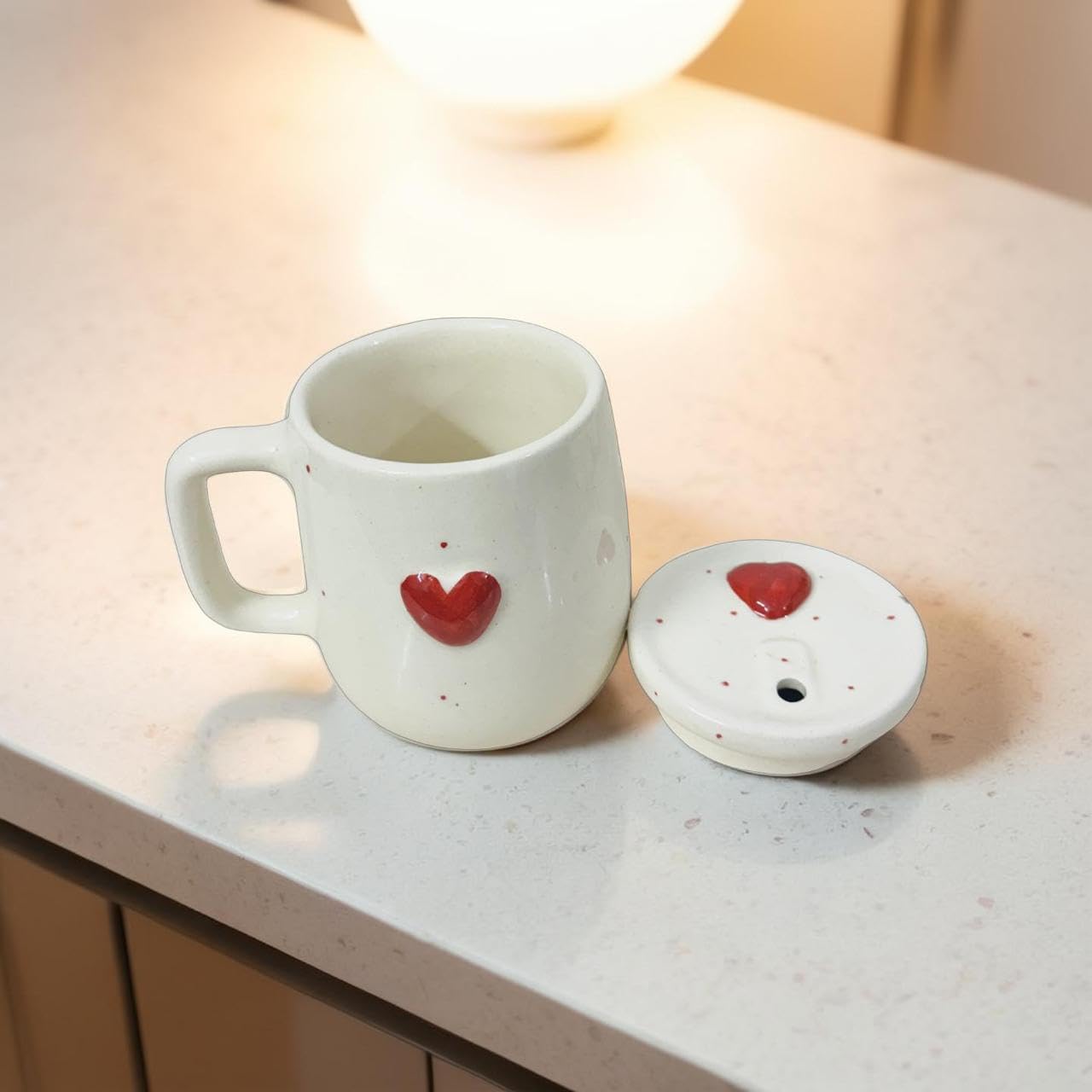 White ceramic mug with red heart design on a light surface