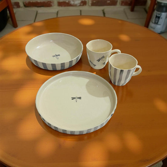 Ceramic tableware set with bowls and cups on a wooden table.