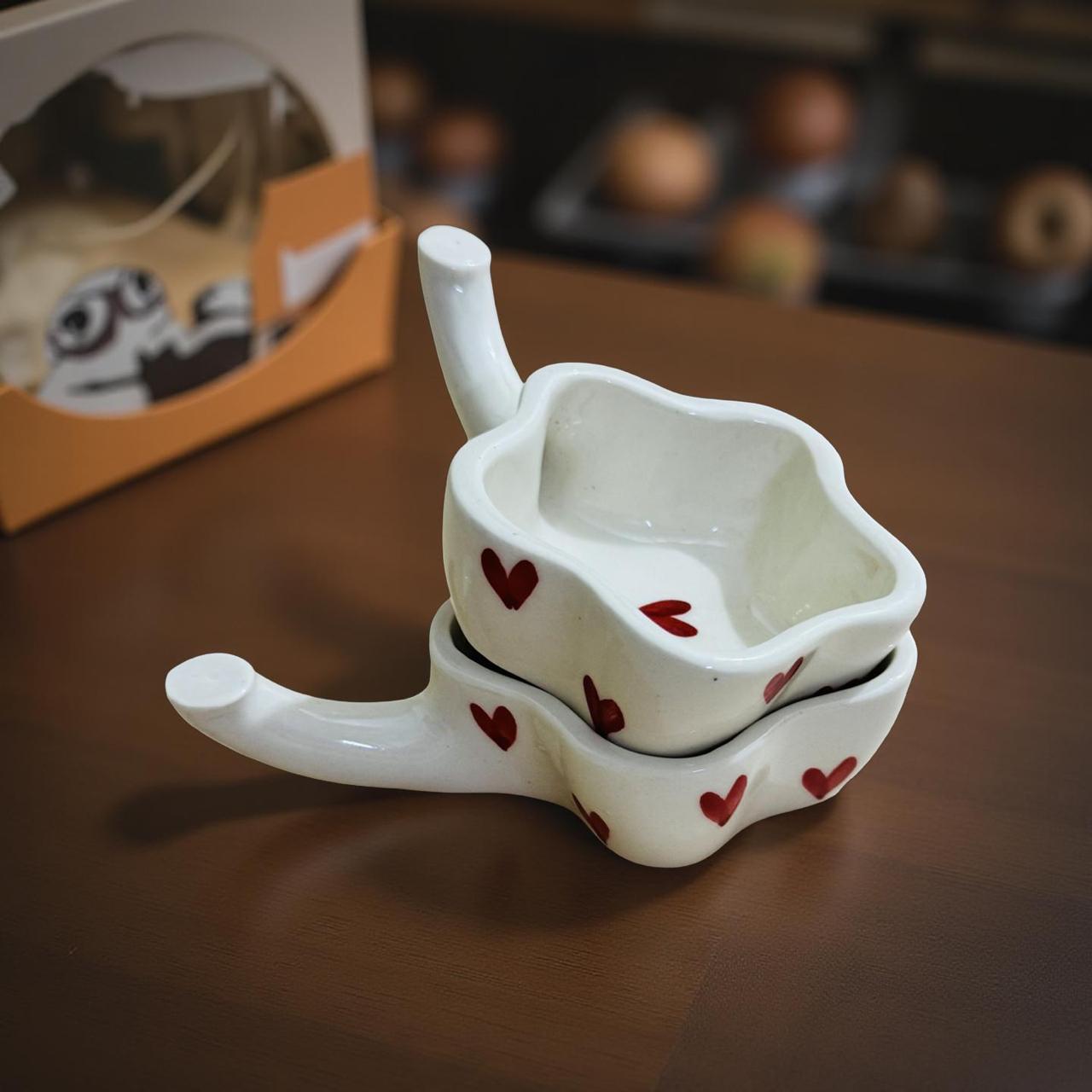 White ceramic measuring cups with red hearts on a wooden surface, with a blurred background.
