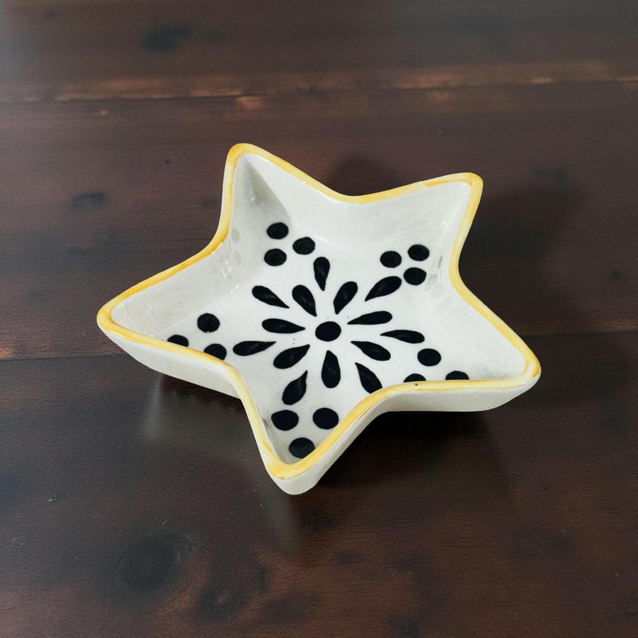 Star-shaped ceramic dish with black floral pattern on a wooden surface