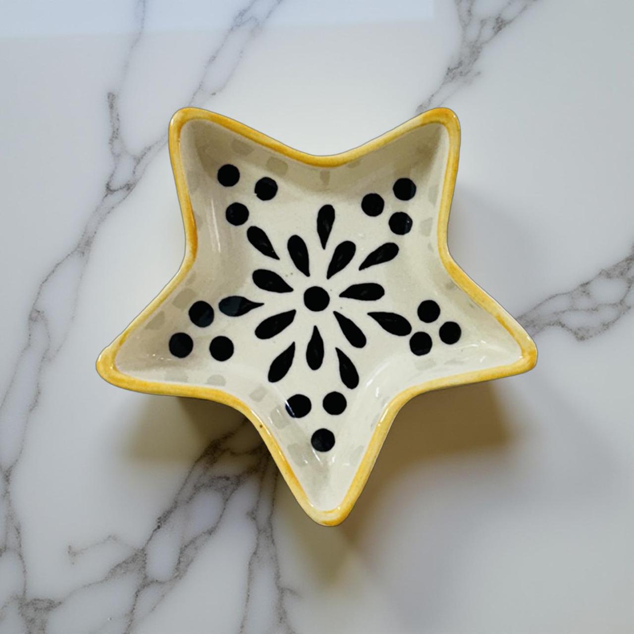 Star-shaped ceramic dish with black floral pattern on a marble surface