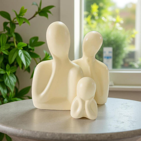 White abstract sculpture of a family on a table with a window and plant in the background