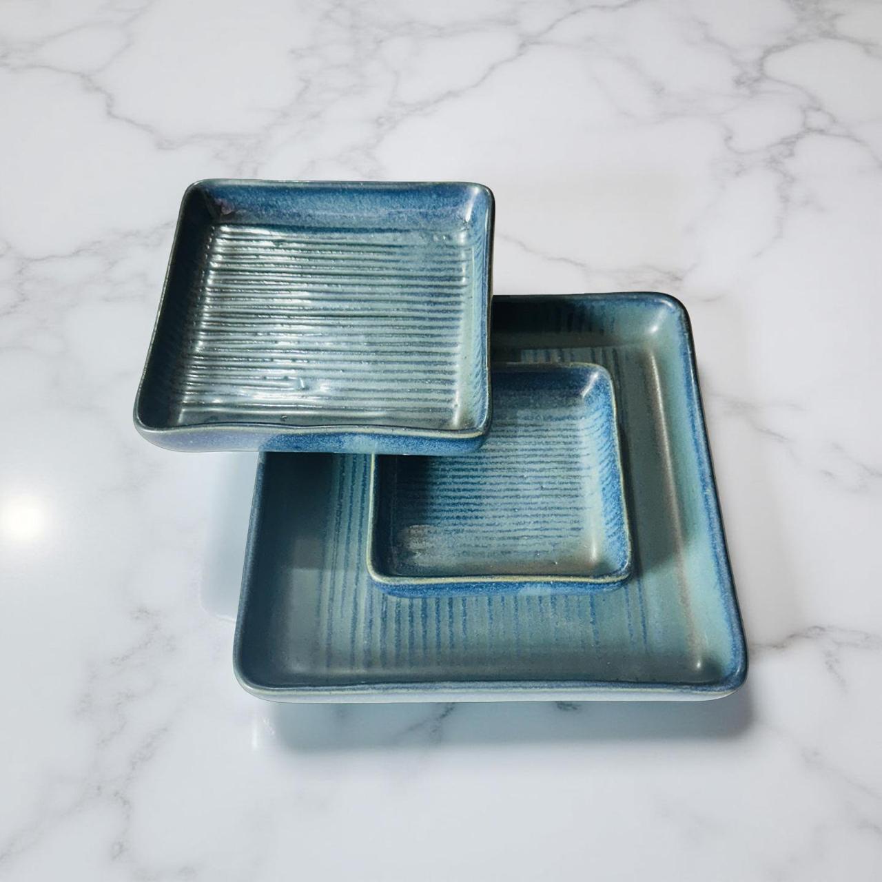Two blue ceramic trays stacked on a marble surface