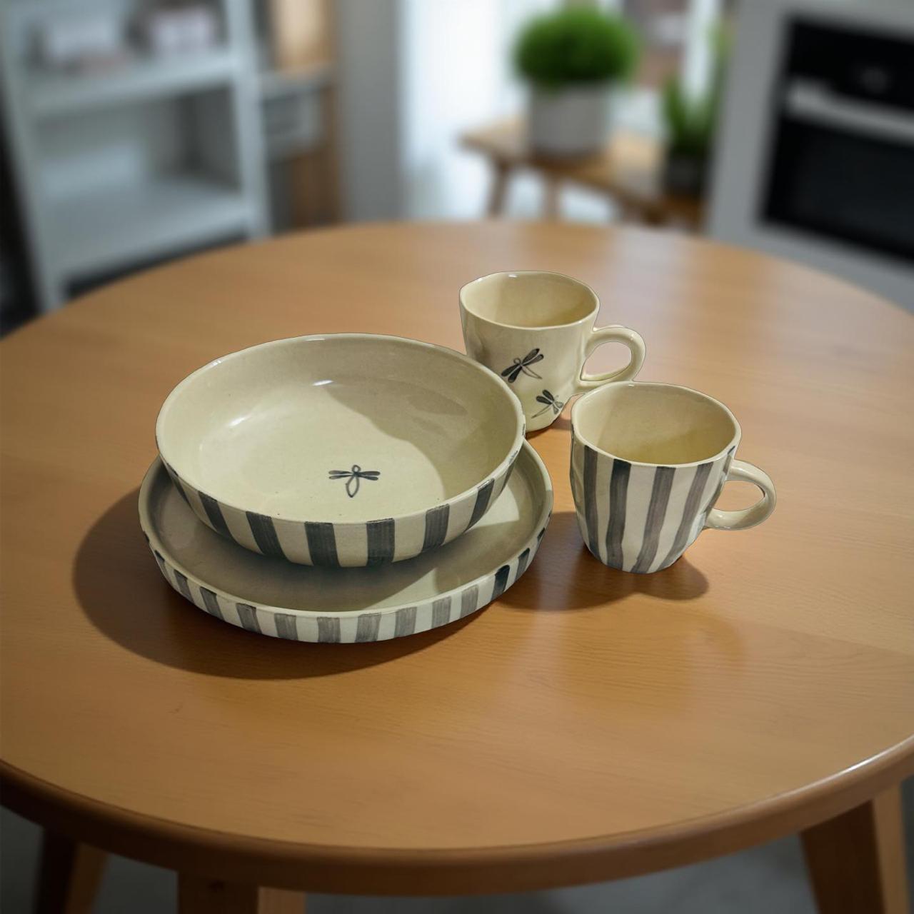 Ceramic bowls and mugs with striped patterns on a wooden table.