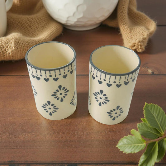 Two ceramic cups with decorative patterns on a wooden surface.