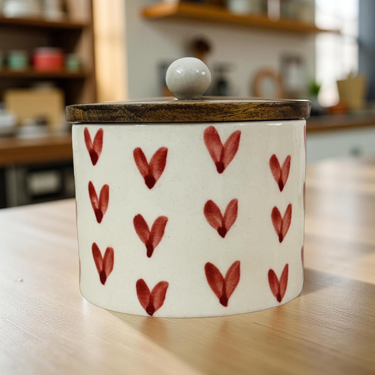 Ceramic container with red heart patterns on a wooden surface