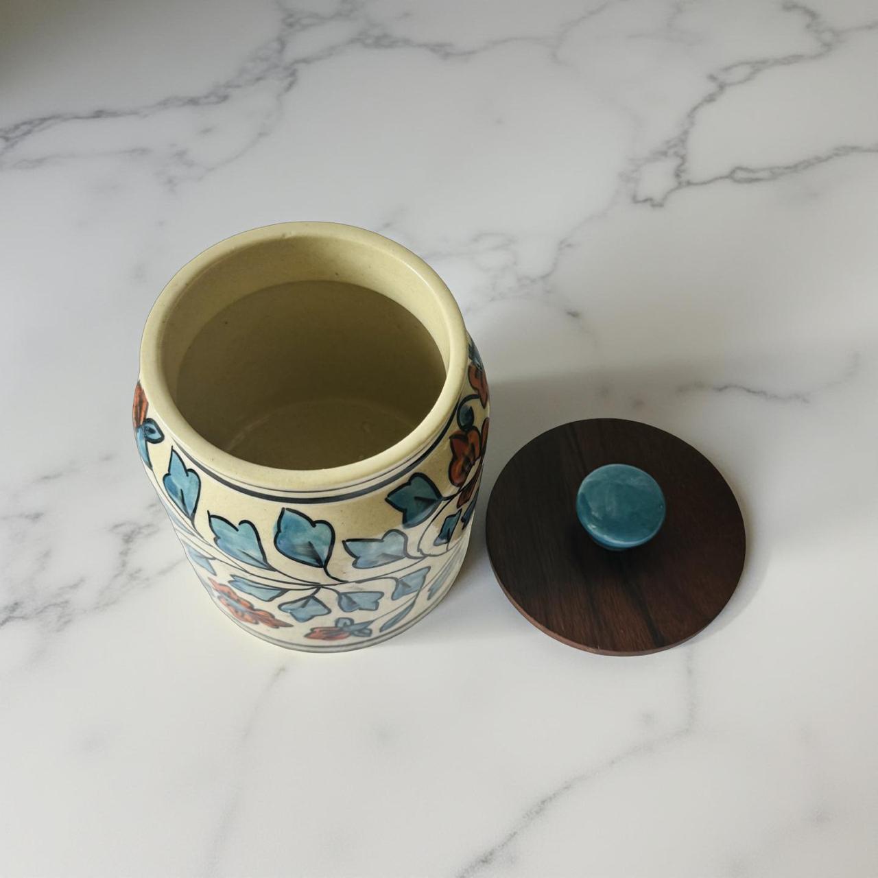 ceramic jar with airtight wooden lid kept on a white marble surface. 