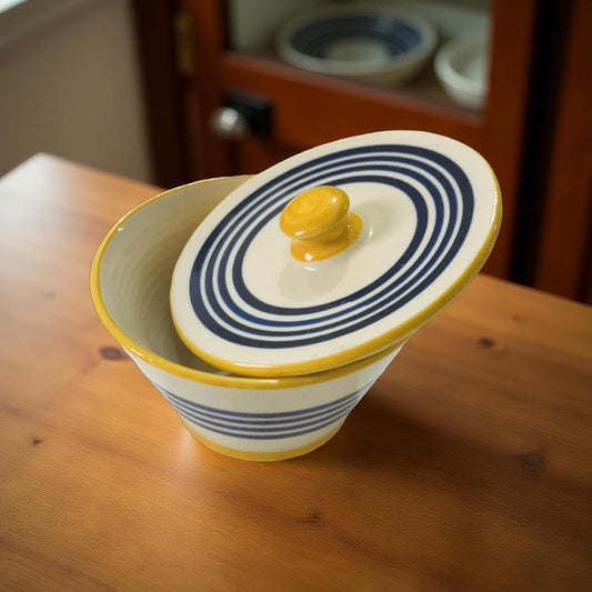 Ceramic container with blue and yellow design on a wooden surface