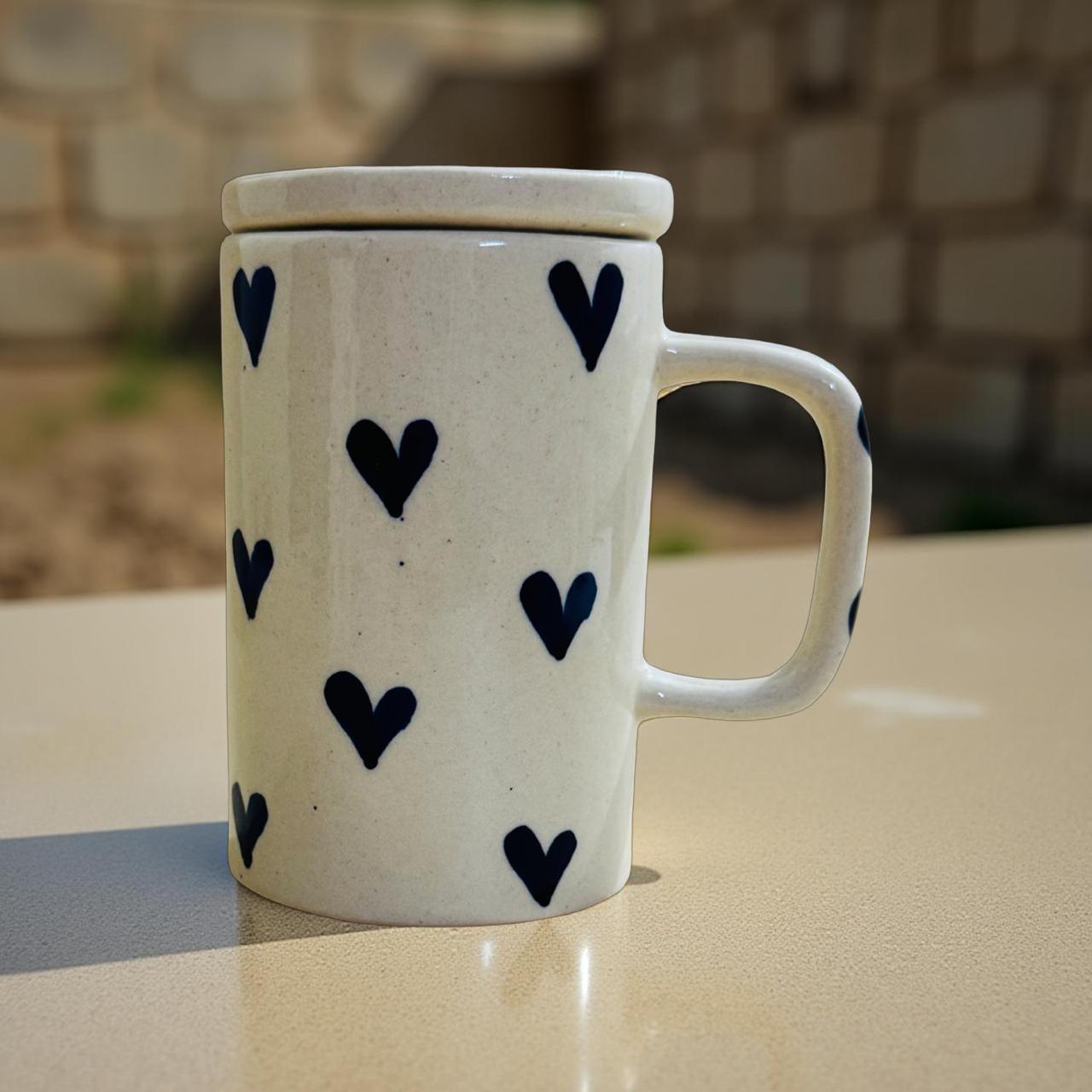 White mug with black heart patterns on a stone surface