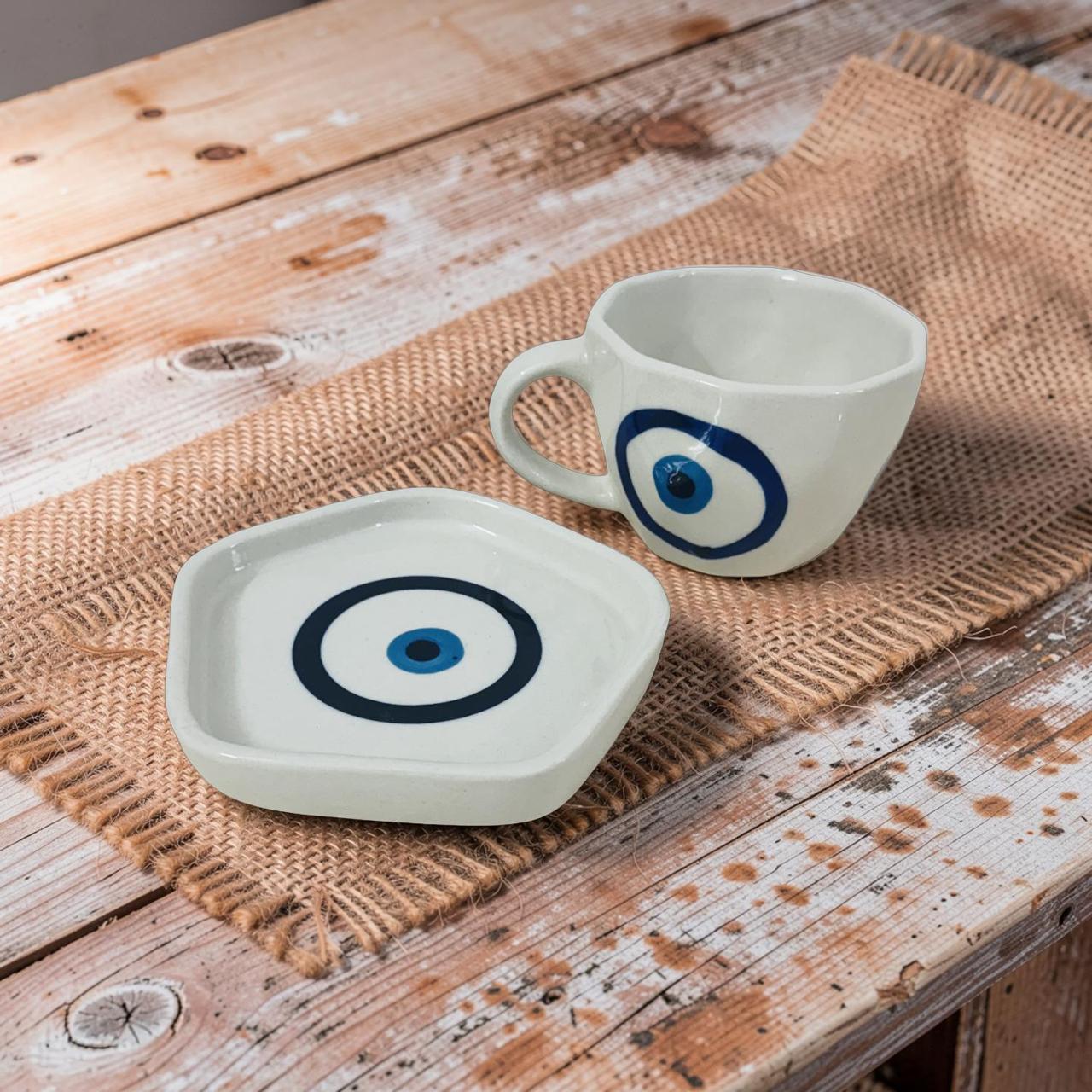 Ceramic cup and saucer with blue eye design on a wooden surface