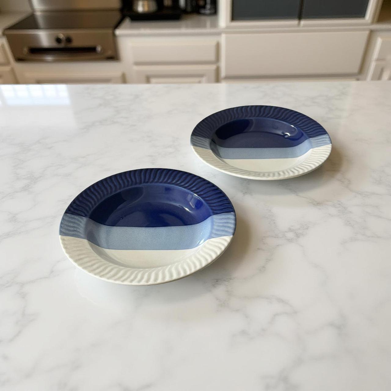 Two blue and white ceramic plates on a marble countertop with a kitchen background.