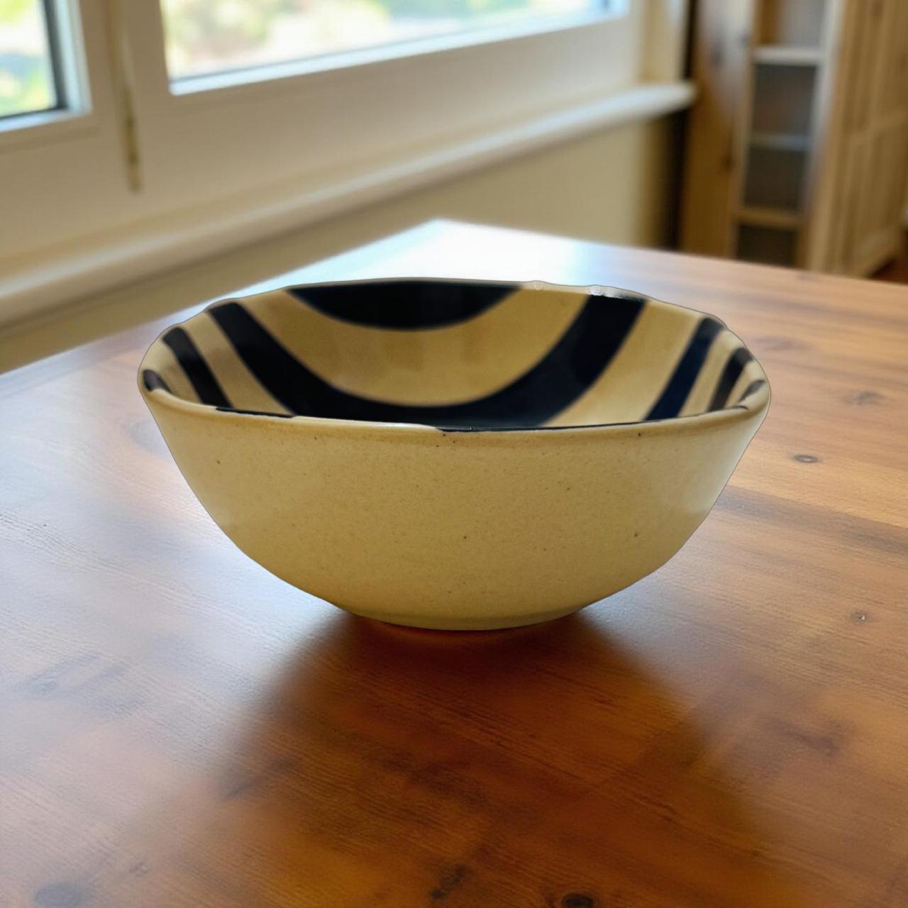 Yellow ceramic bowl with black stripes on a wooden table
