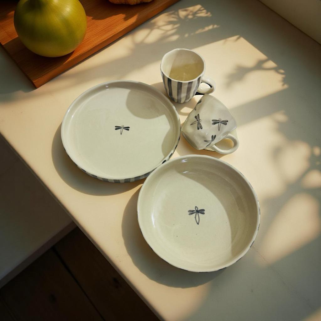 Ceramic tableware set with dragonfly design on a light surface