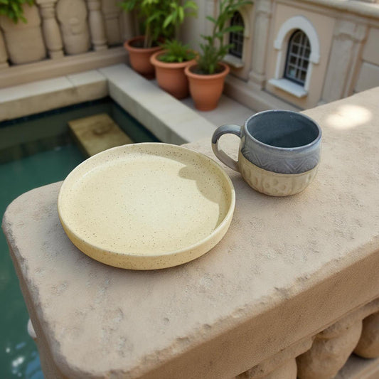 Neutral beige ceramic plate with a grey-beige mug on a rustic ledge near water – cozy and aesthetic solo dining set.