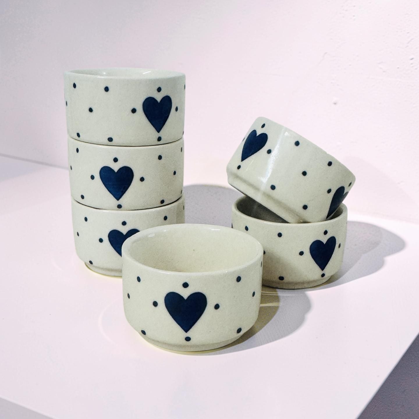 Set of ceramic bowls with blue heart and dot patterns on a light background