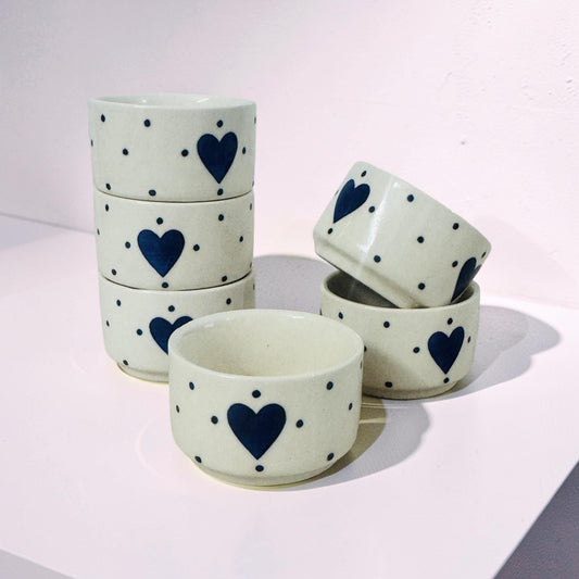 Set of ceramic bowls with blue heart and dot patterns on a light background