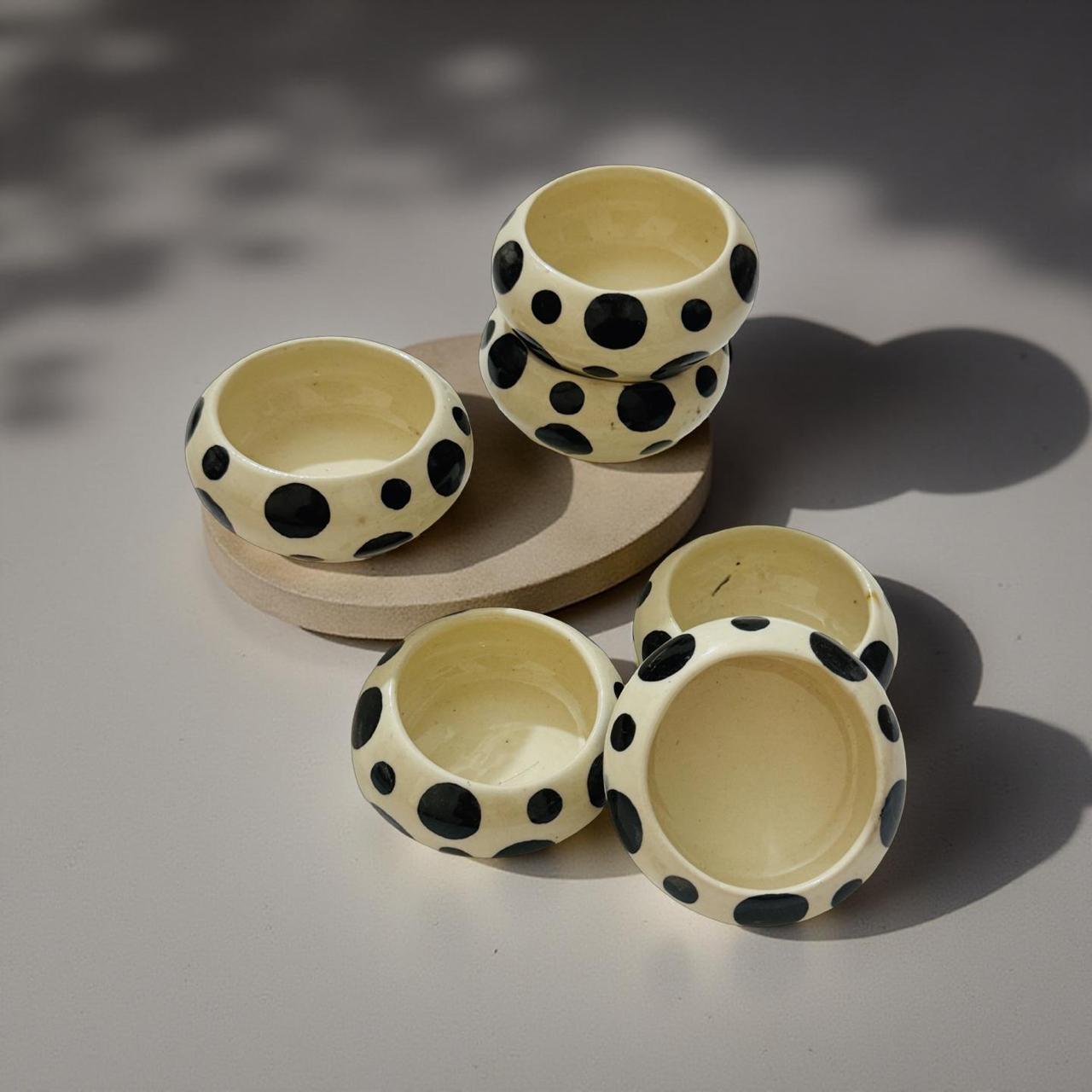 Set of ceramic bowls with black polka dot patterns on a neutral background