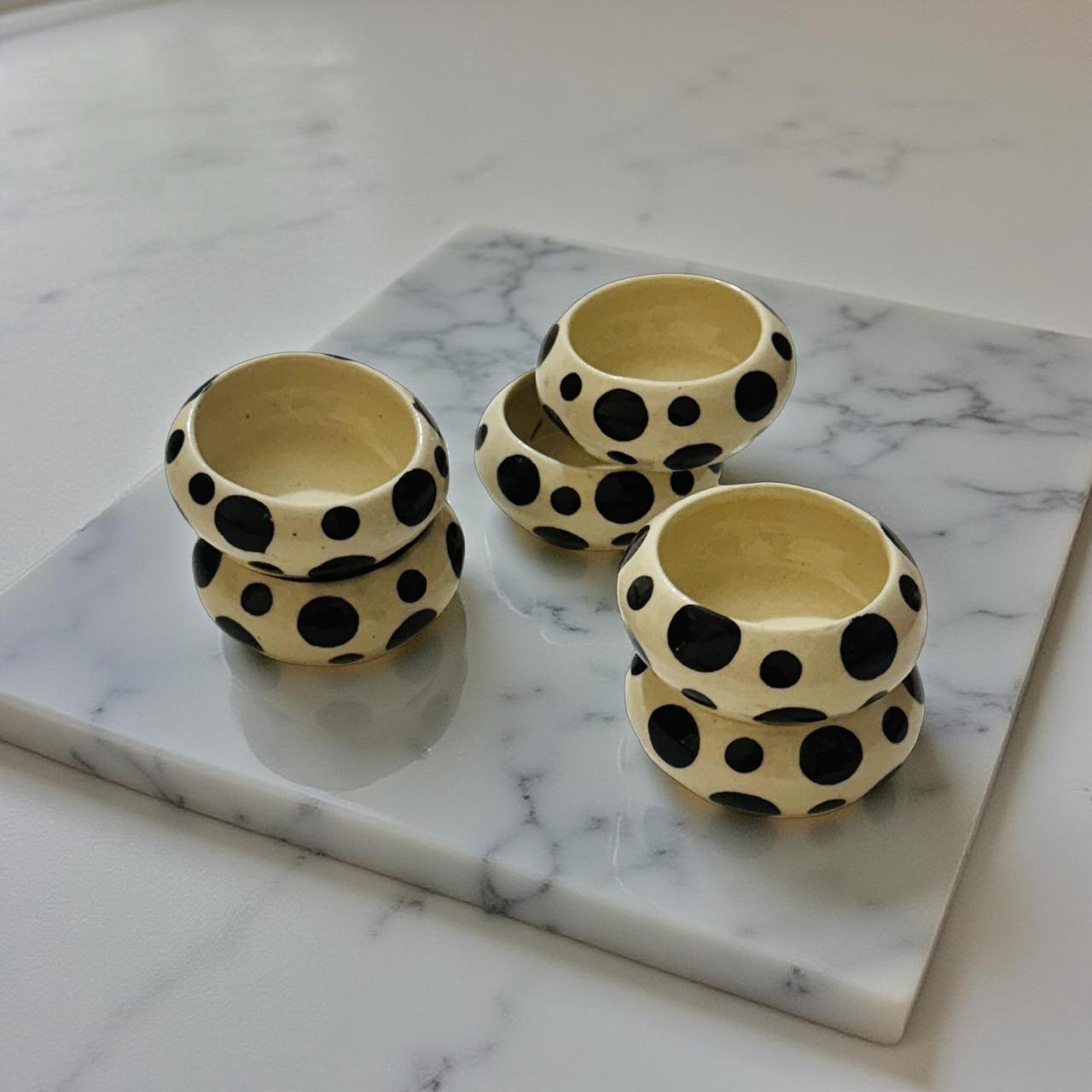 Set of three ceramic bowls with black polka dot patterns on a marble surface