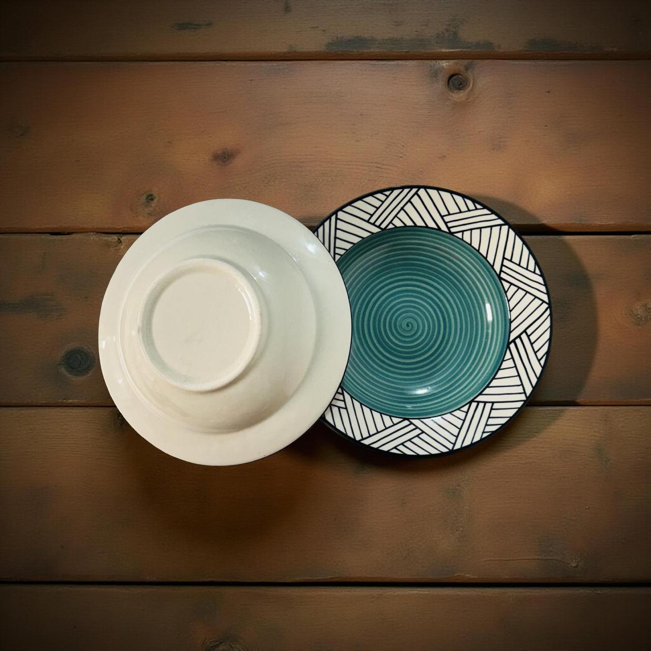 Two ceramic plates, one white and one teal with black patterns, on a wooden surface.