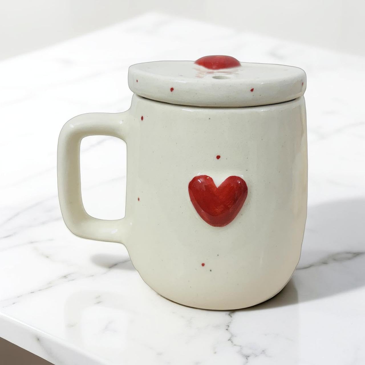 White ceramic mug with red heart design on a marble surface