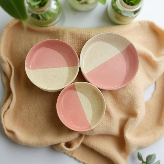 Set of three ceramic plates with pink and beige design on a beige cloth