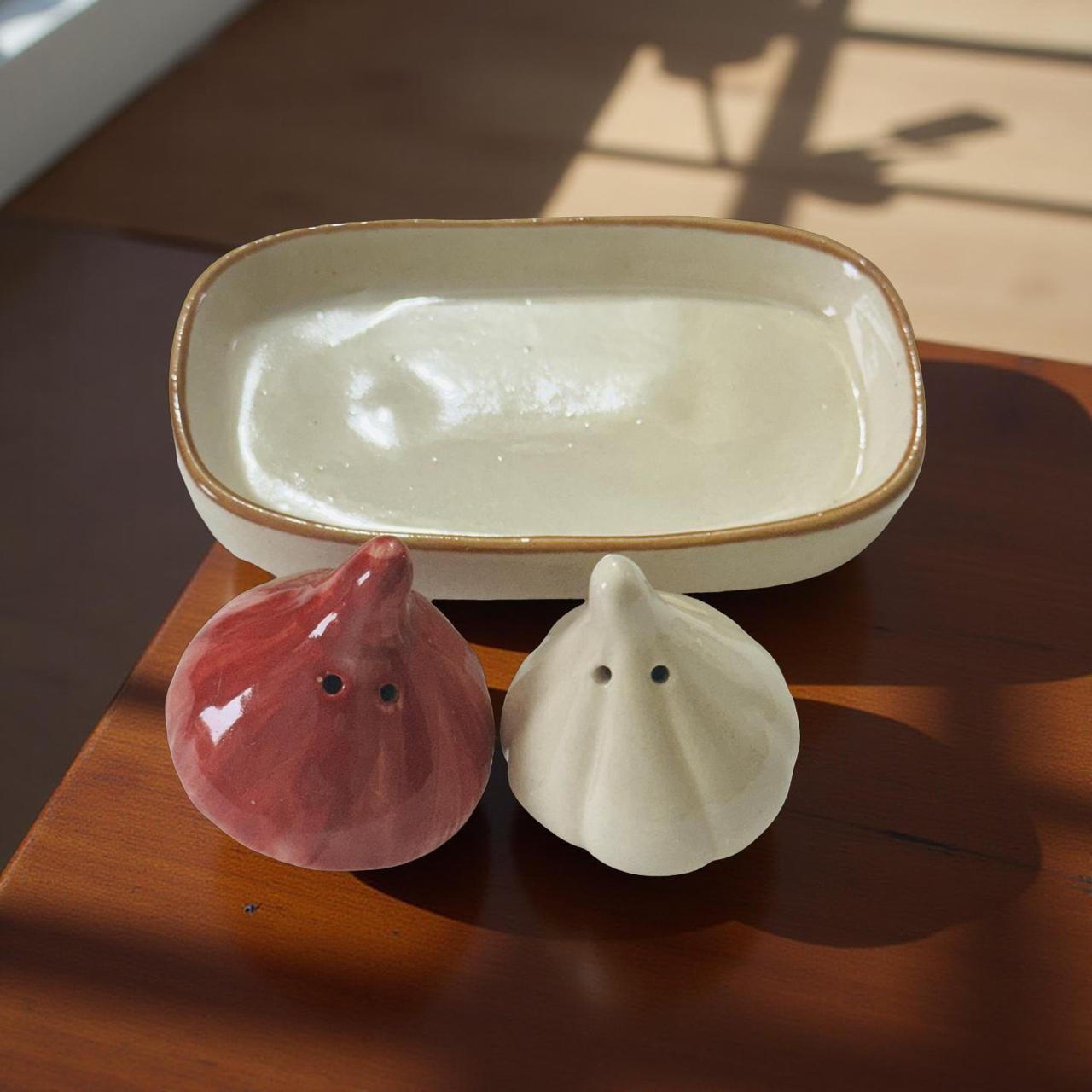Ceramic container with two small figurines on a wooden surface