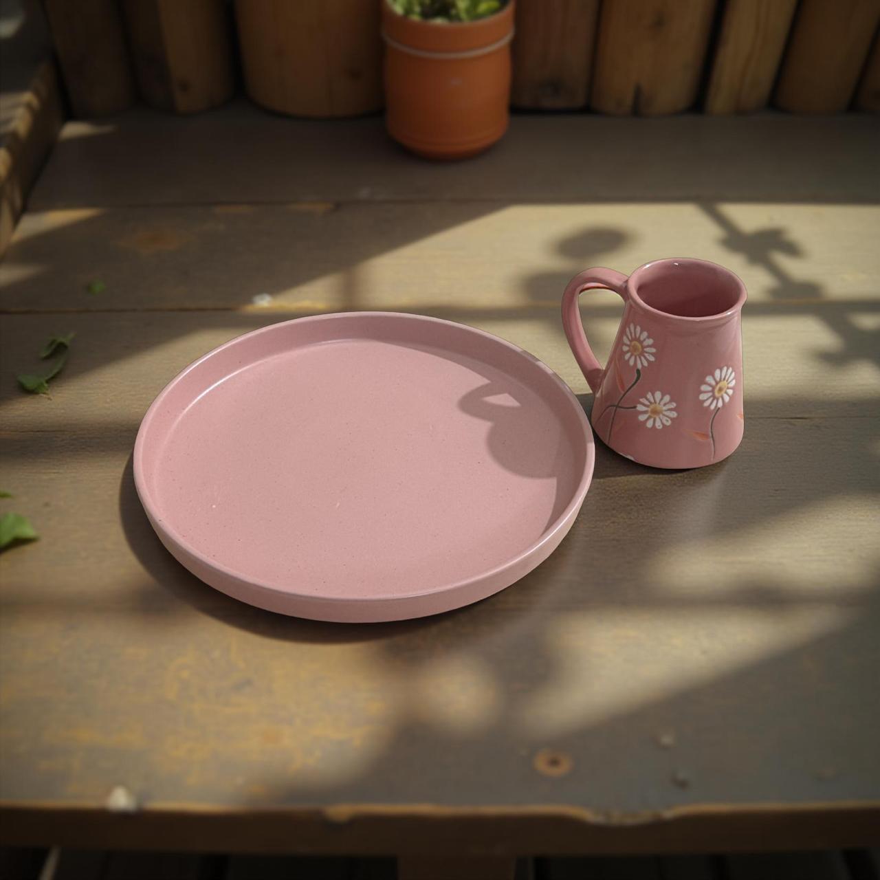 Pink ceramic plate and mug on a wooden surface with potted plants in the background