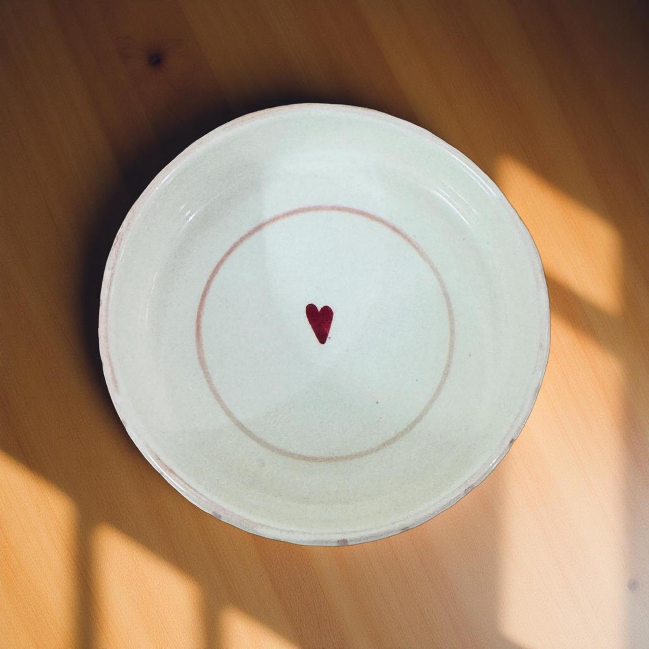 white ceramic bowl with  red heart on a wooden surface