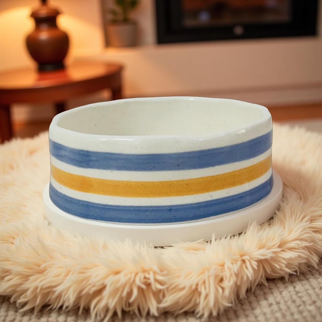 Ceramic bowl with blue and orange stripes on a fluffy surface