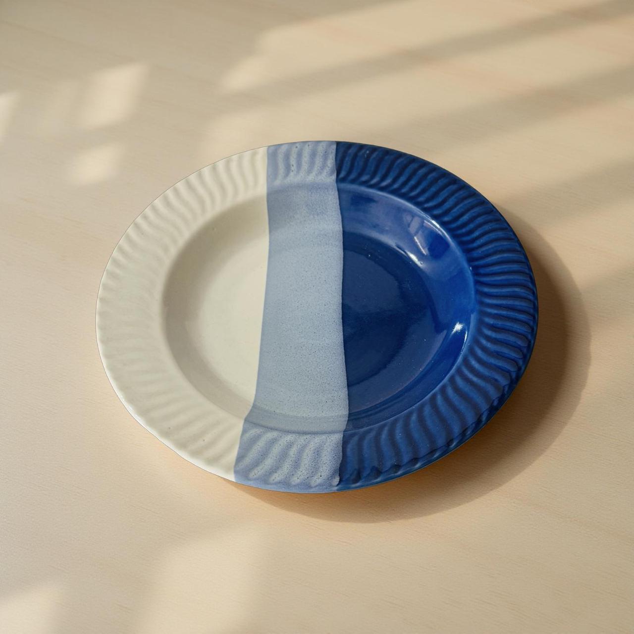 half white and  blue ceramic plates, one white and one blue, on a beige surface.
