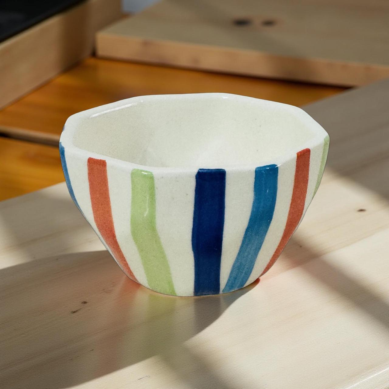 Ceramic bowl with colorful stripes on a wooden surface