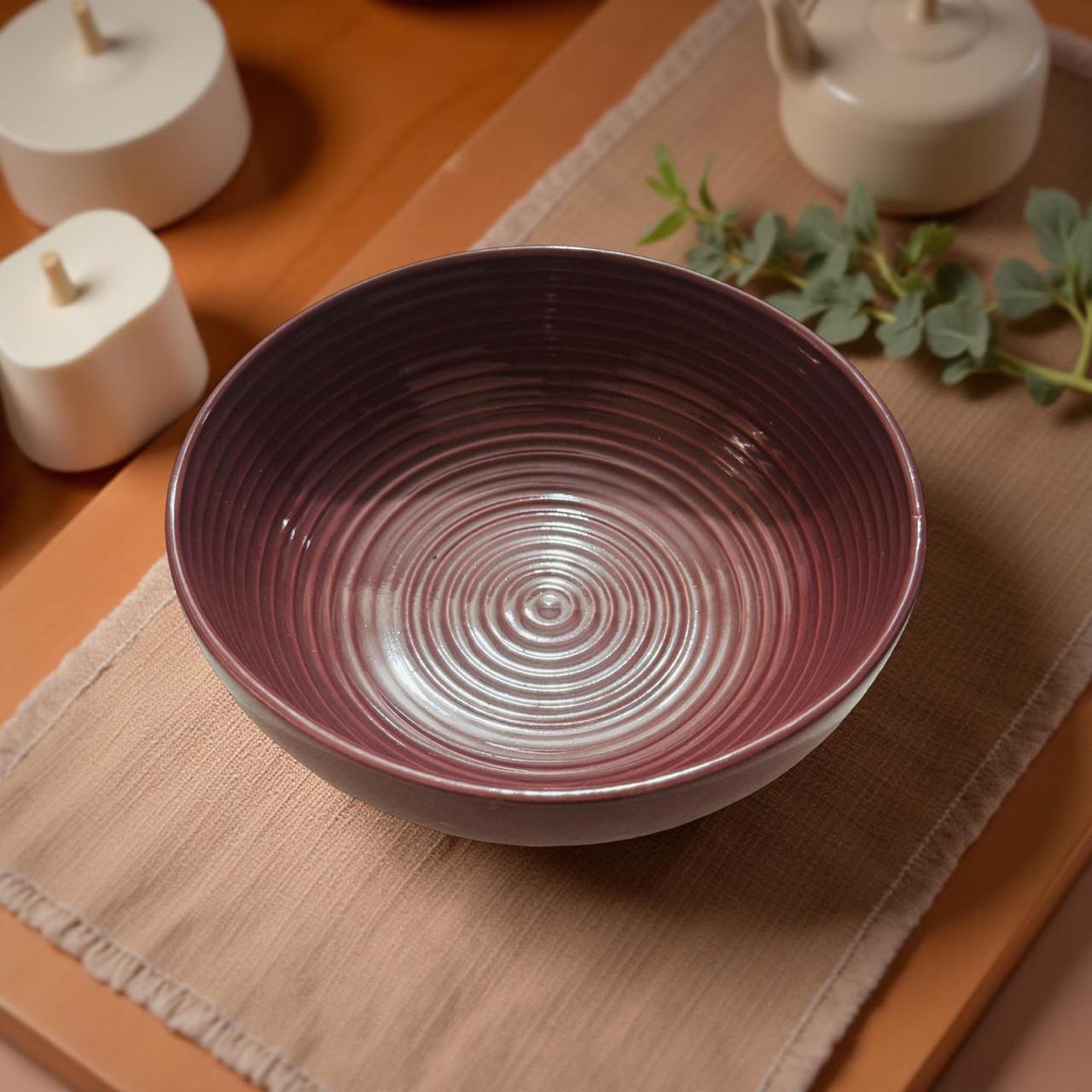 Purple ceramic bowl on a wooden table with decorative items