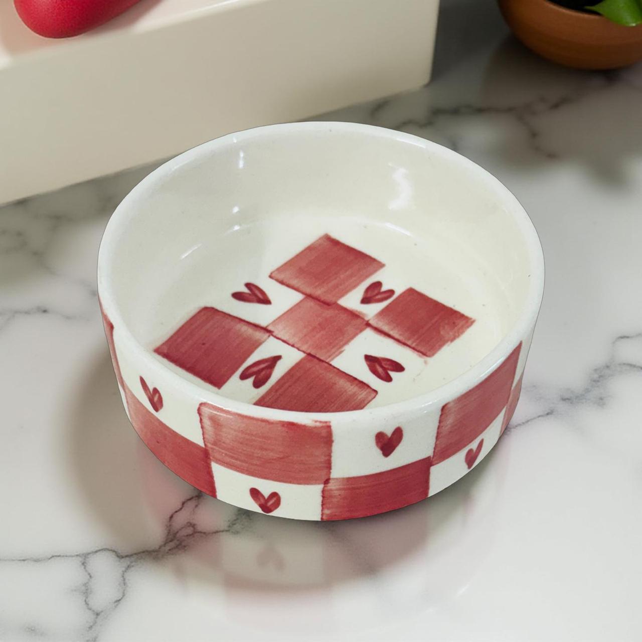 Decorative ceramic bowl with red and white pattern on a marble surface