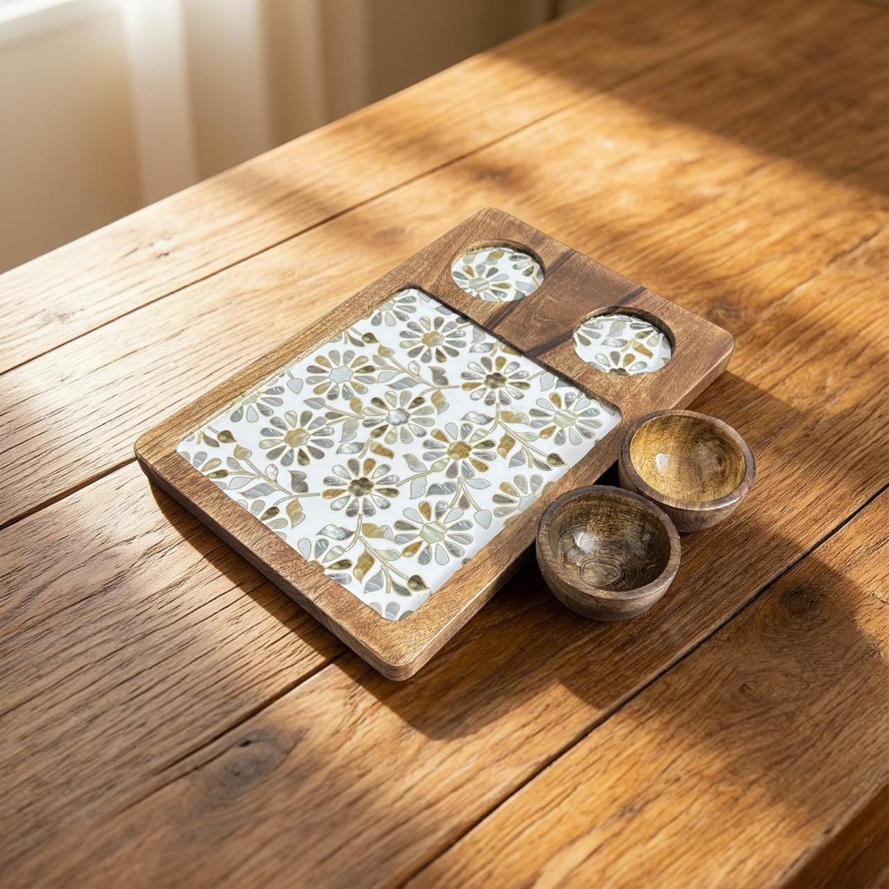 Wooden tray with floral pattern and two small wooden bowls on a wooden surface
