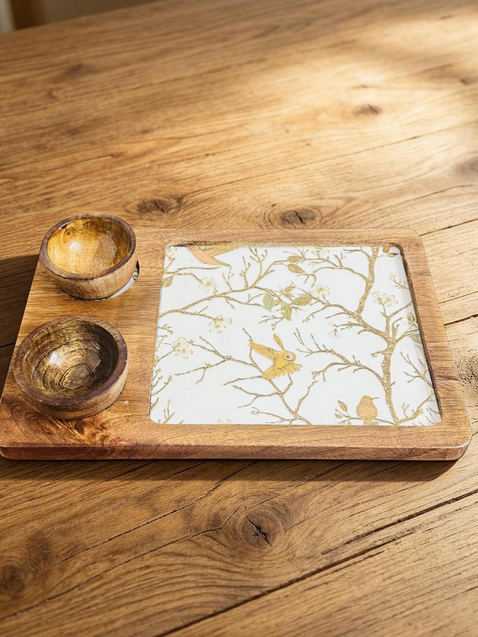 Wooden tray with ceramic plate featuring floral design and two wooden bowls on a wooden surface.