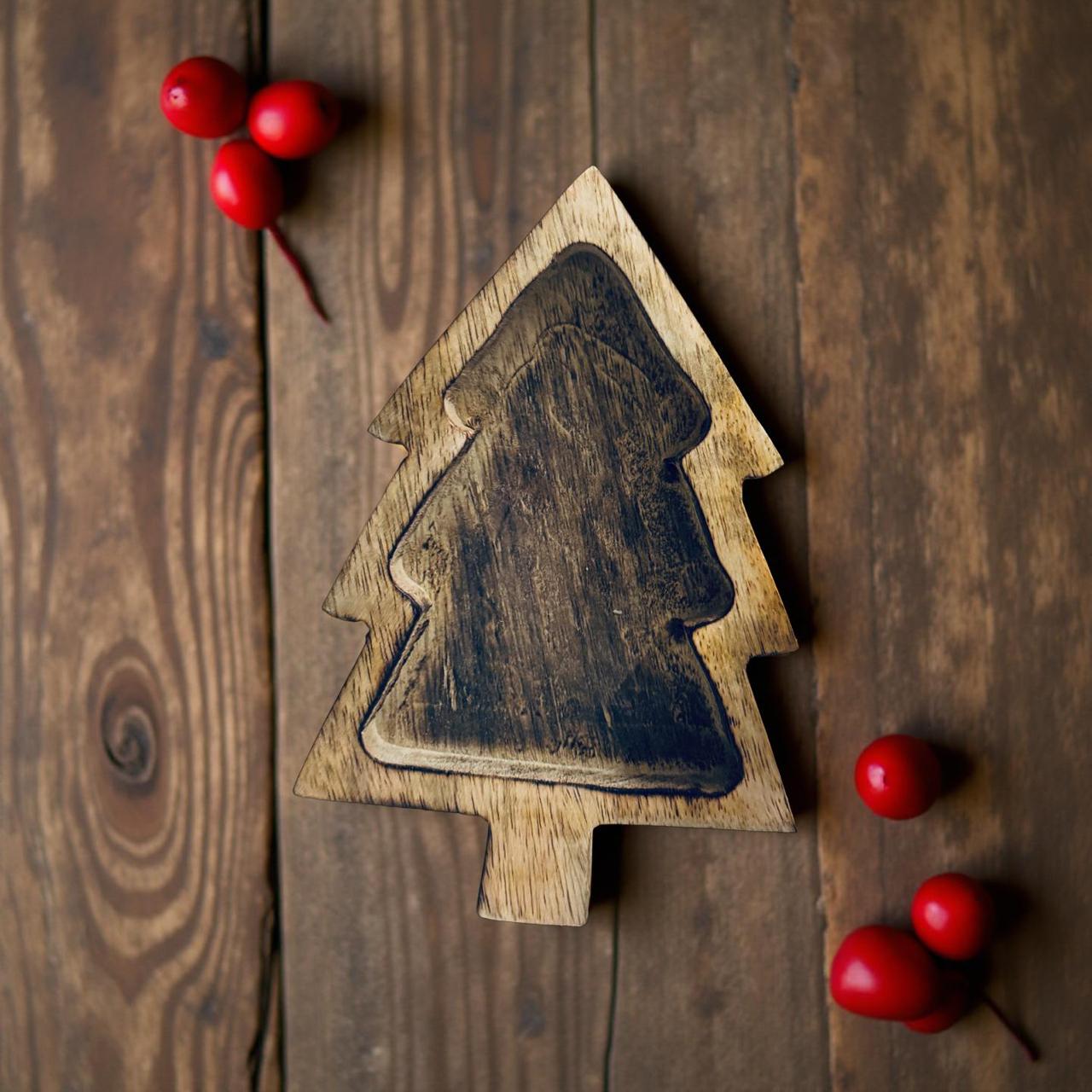 Wooden Christmas tree decoration on a wooden surface with red berries.
