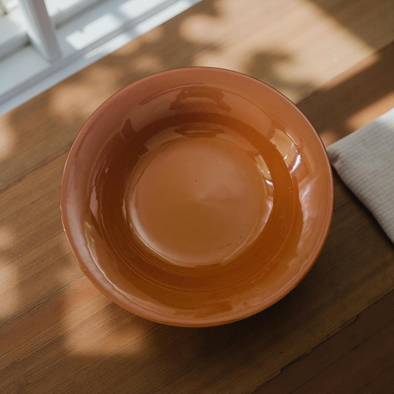 Orange ceramic bowl on a wooden surface with natural light
