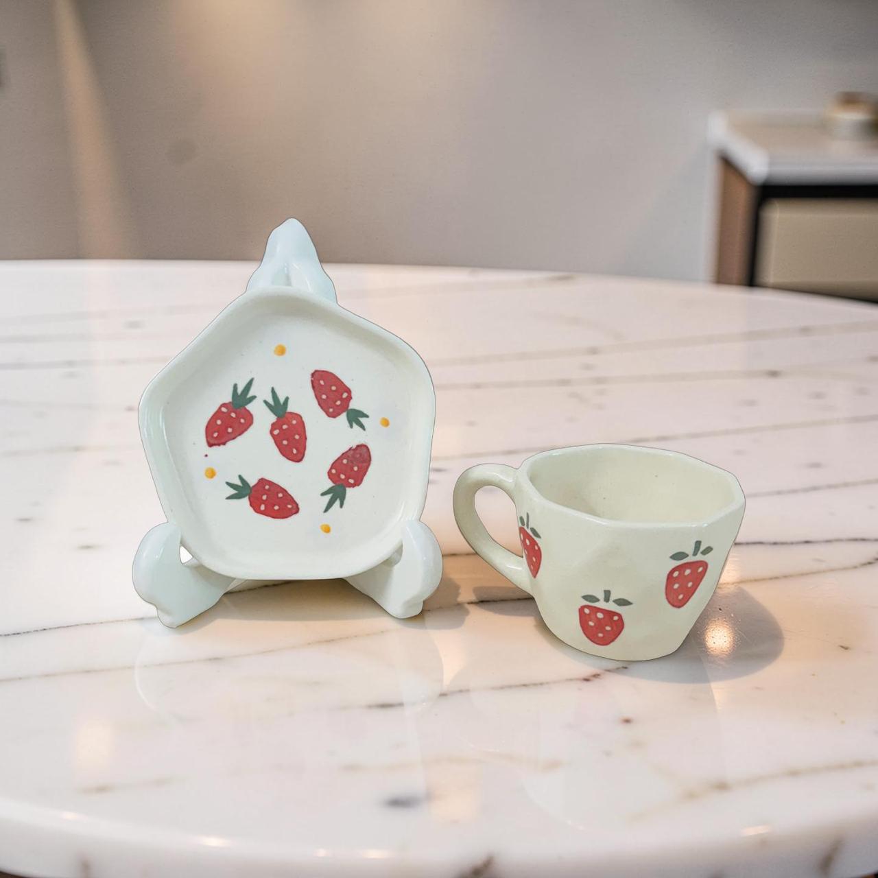 Ceramic dish and mug with strawberry design on a marble surface