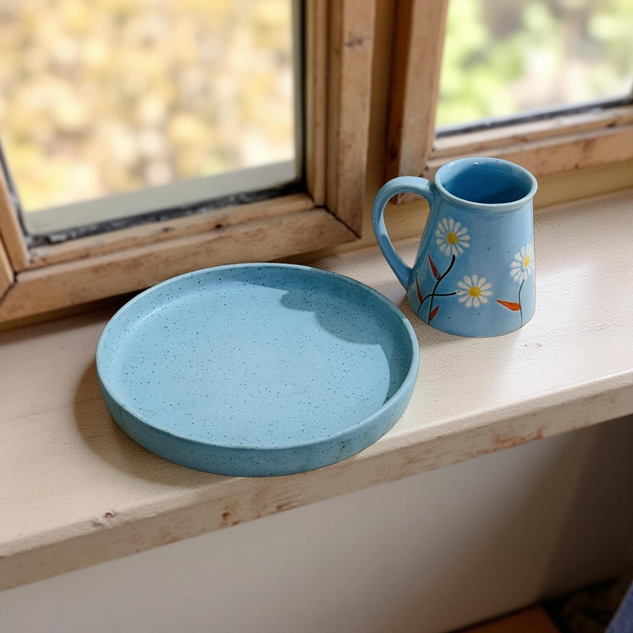 Blue ceramic plate and mug with floral design on a windowsill