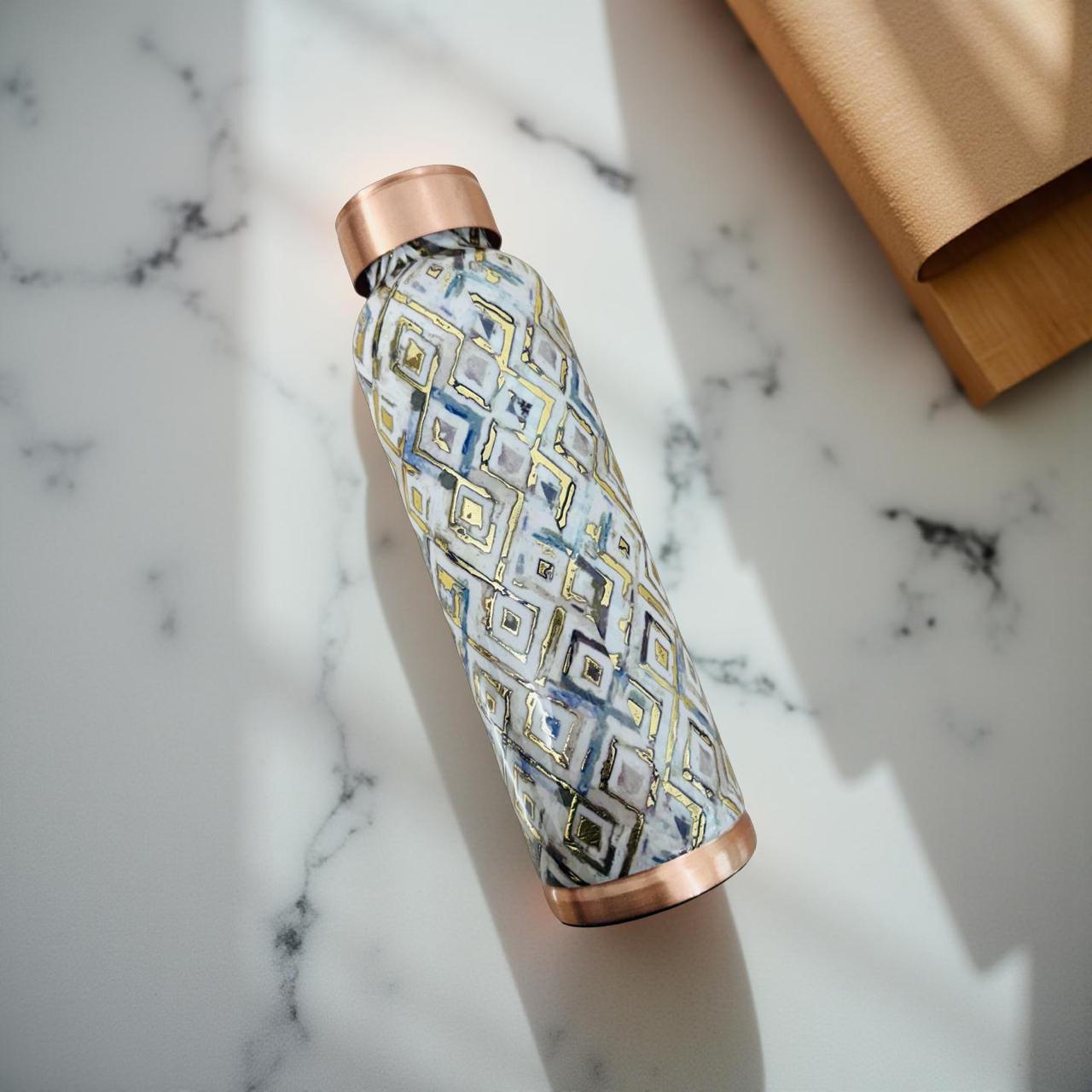 Patterned water bottle with copper cap on a marble surface
