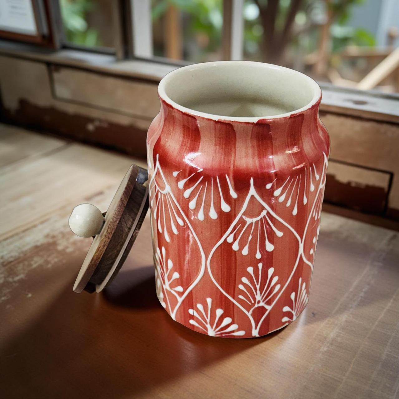 Red ceramic jar with white patterns on a wooden surface