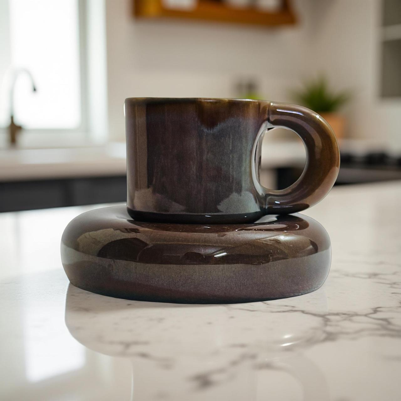 Brown ceramic cup and saucer on a marble countertop with a kitchen background
