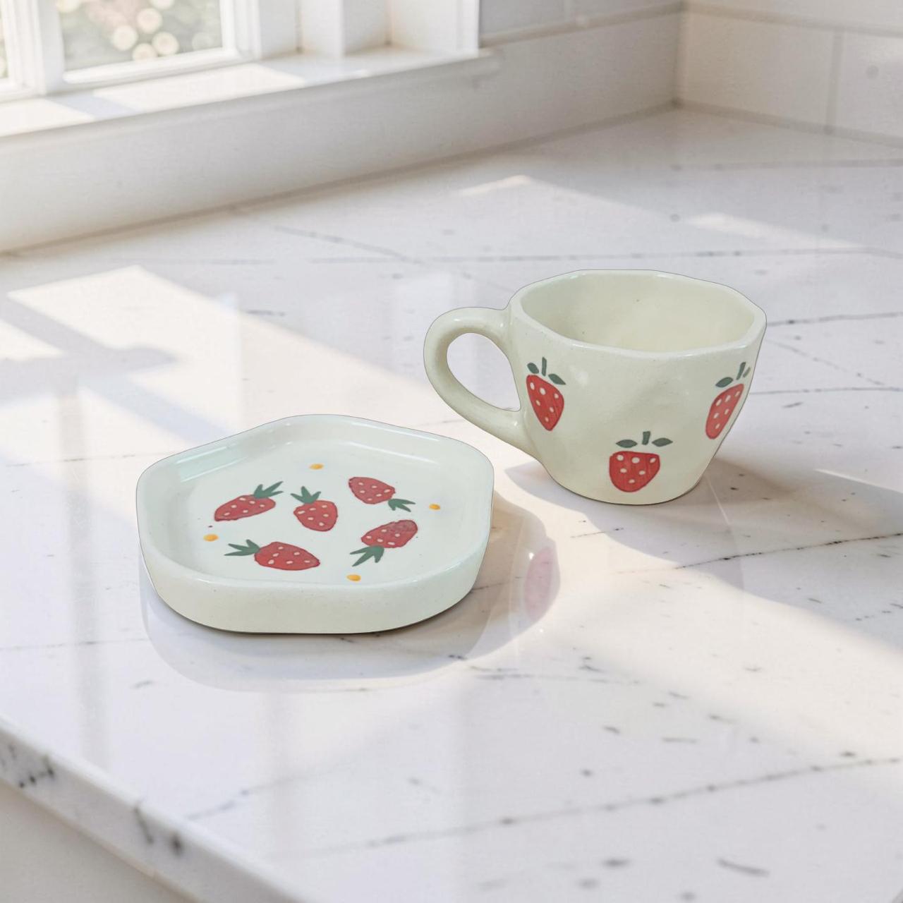 Ceramic cup and saucer with strawberry design on a marble surface