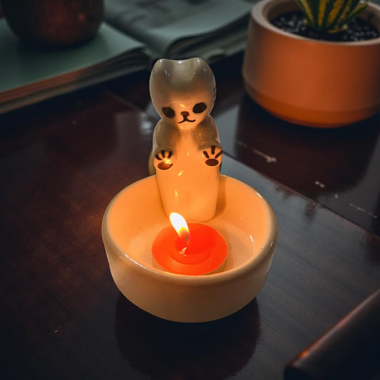 Candle with a bear-shaped wick holder on a dark surface