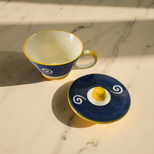 Ceramic cup and saucer with blue and yellow design on a marble surface