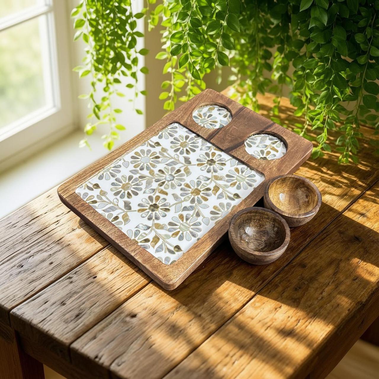 Decorative wooden tray with floral patterns on a wooden table with plants in the background