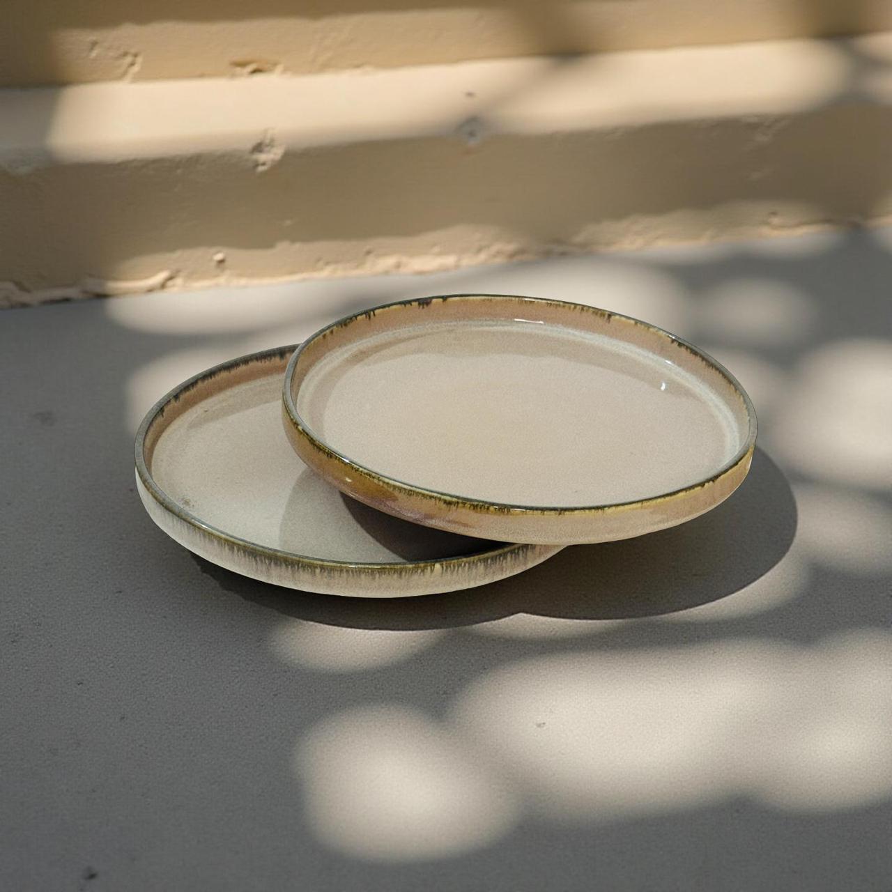 Two ceramic plates with a rustic finish on a textured surface.